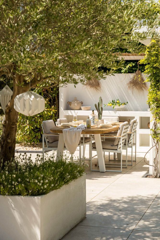 Vooraanzicht van een veranda met een Ibiza tuinstijl, voorzien van een trendy vormgegeven tuinset in zandkleur.