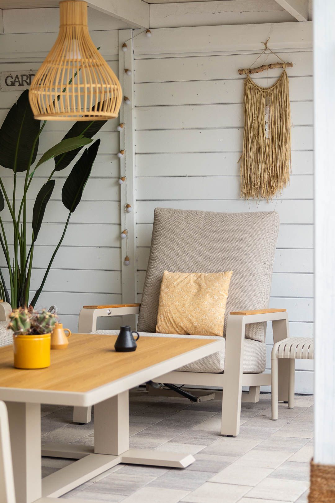 Comfortabele loungestoel met lichte kussens onder de overkapping