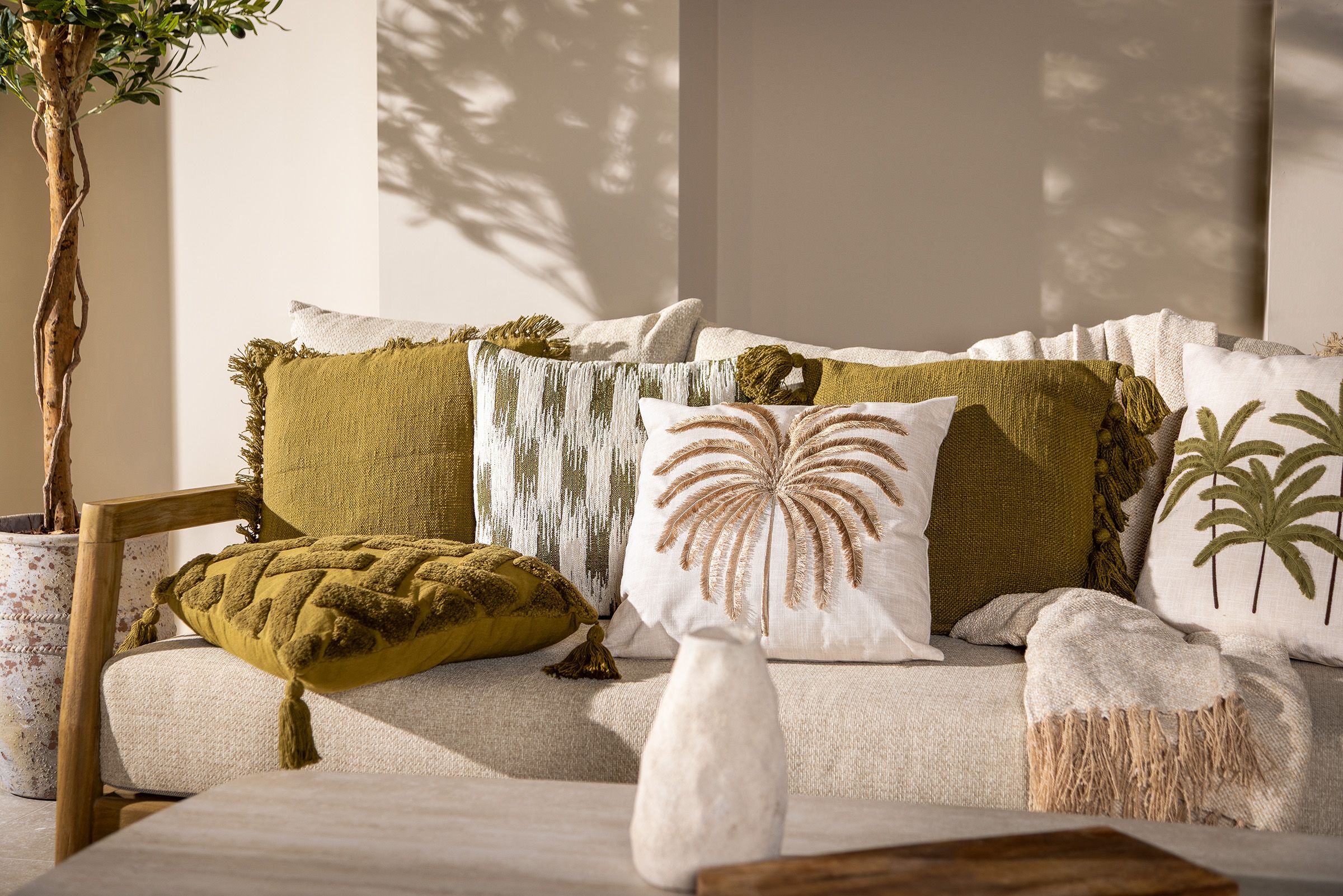 Close-up van een comfortabele loungebank met groene en beige sierkussens voor extra ondersteuning in de rug.