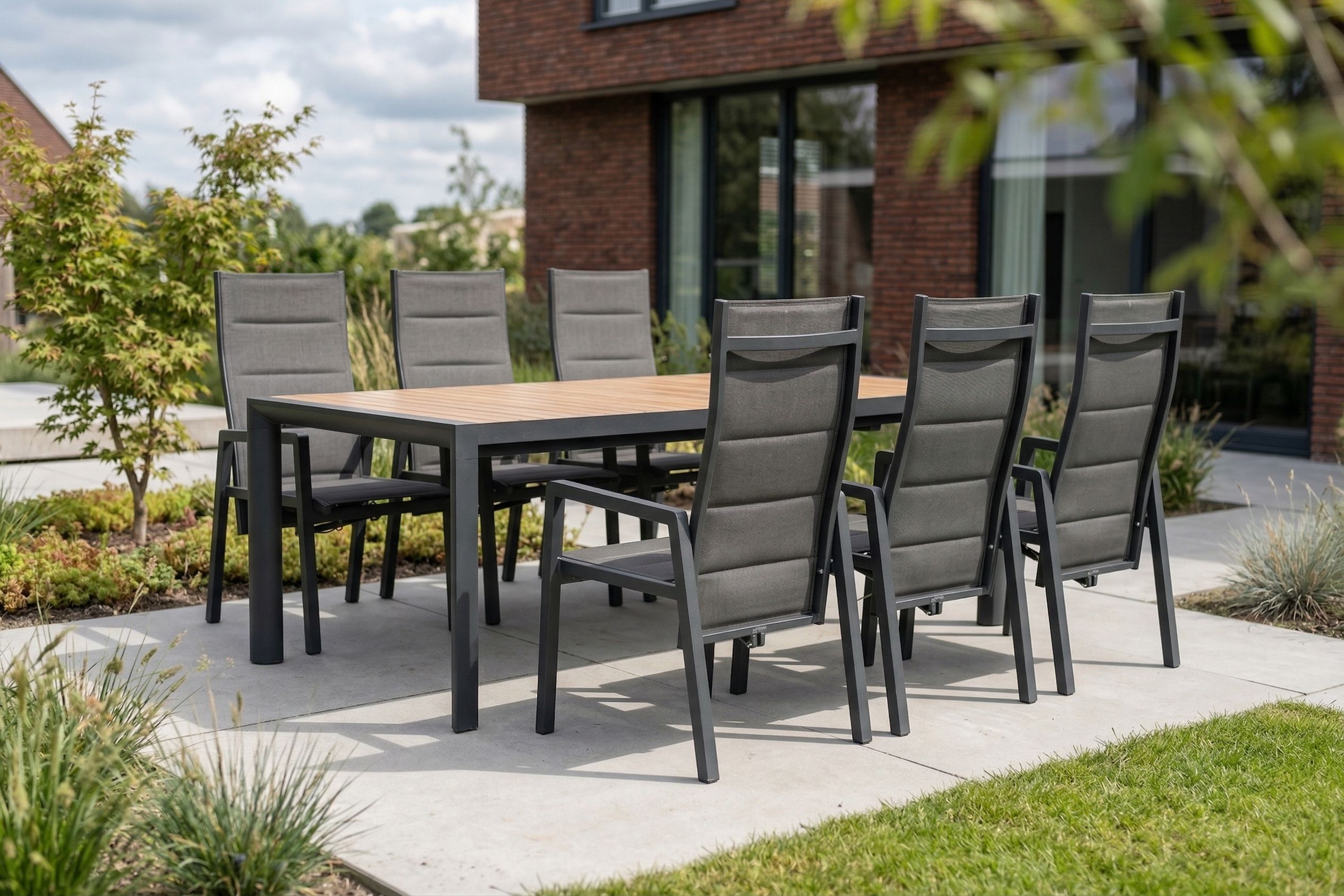 Roestvrije aluminium tuinset met antraciet stoelen en houten tafelblad op een modern terras.