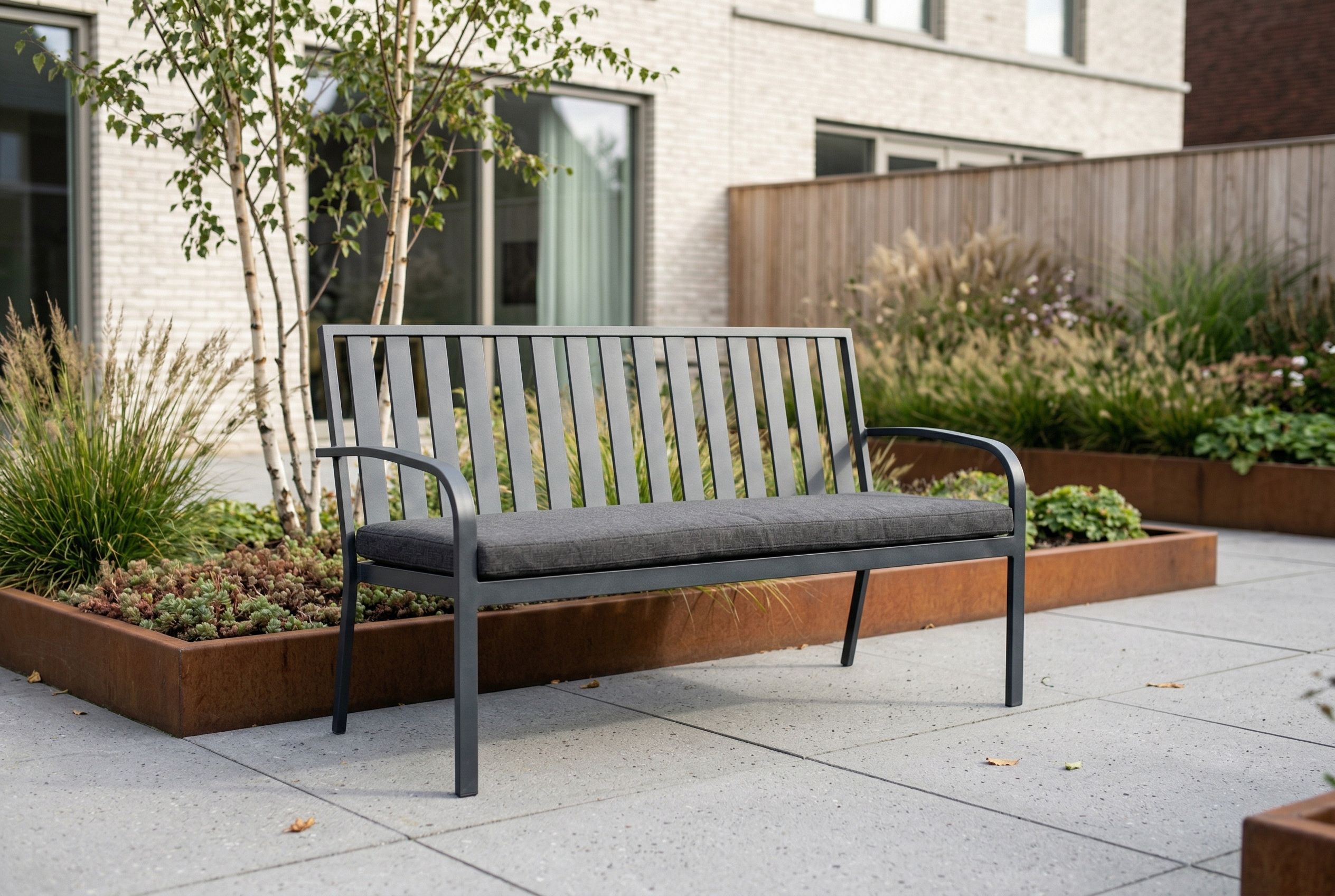 Moderne aluminium tuinset met zes tuinstoelen op een strak betegeld terras, geplaatst voor een lichte houten schutting met groene beplanting en een grote terracotta bloempot.