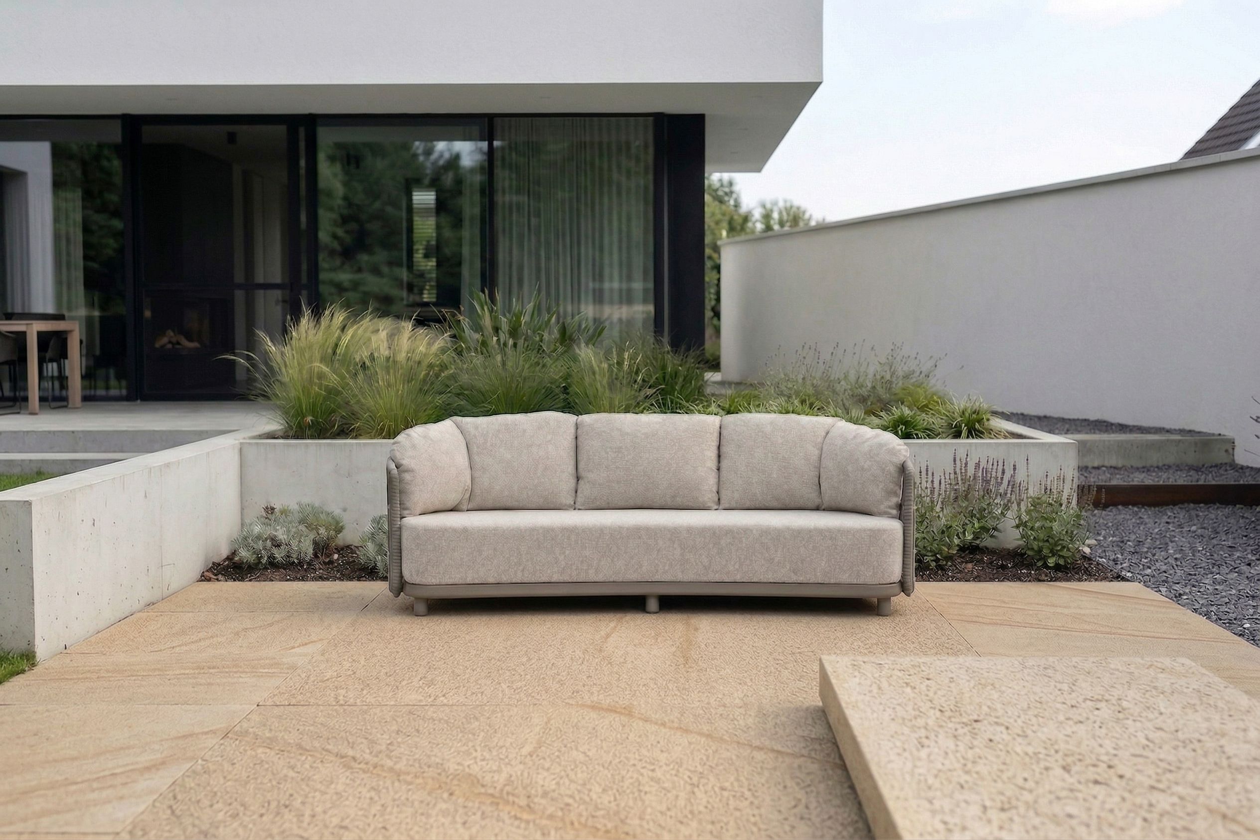 Moderne aluminium tuinset met zes tuinstoelen op een strak betegeld terras, geplaatst voor een lichte houten schutting met groene beplanting en een grote terracotta bloempot.