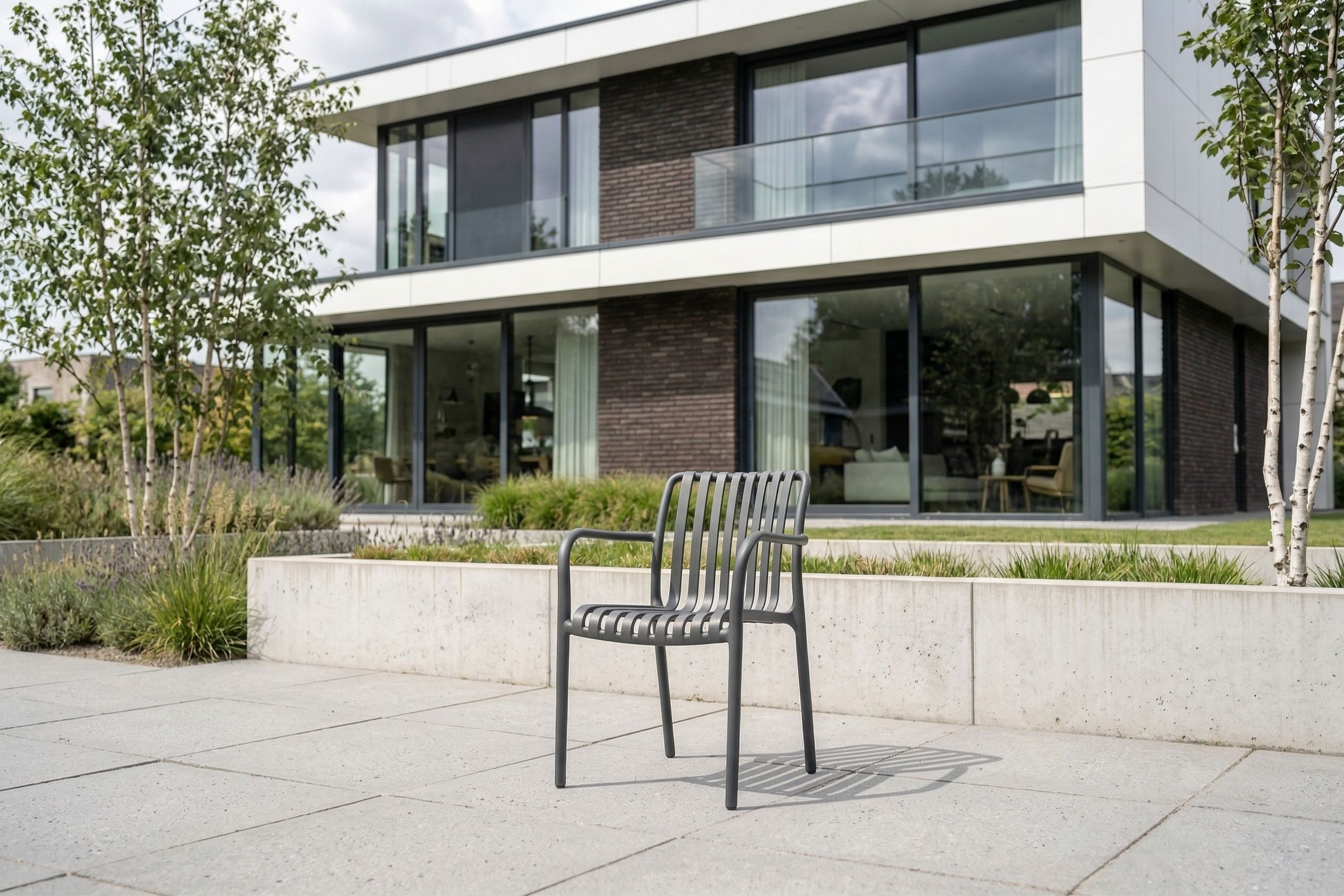 Antraciet kunststof tuinstoel op modern terras bij luxe woning met aangelegde tuin