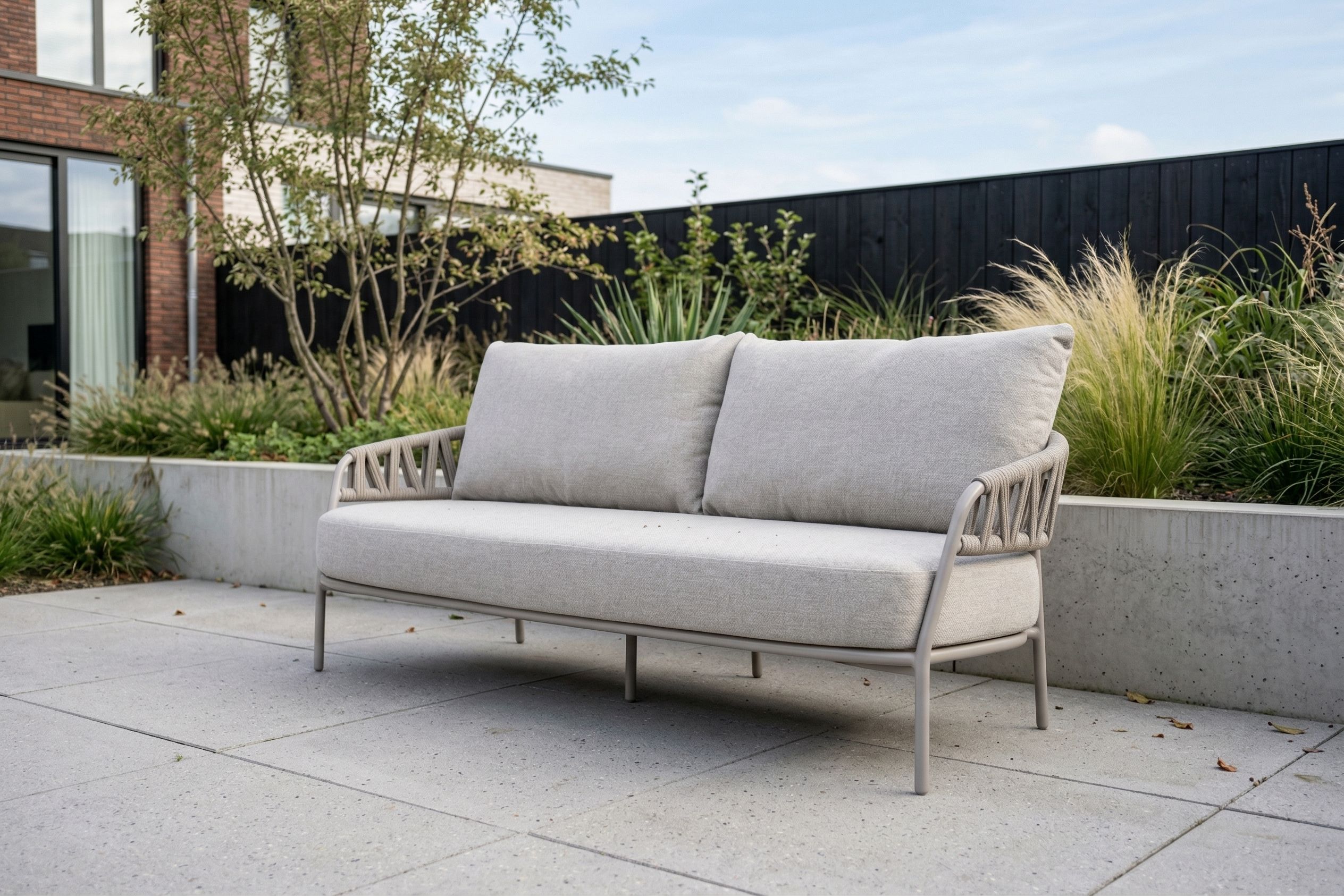 Luxe 2.5-zits lounge tuinbank van aluminium en rope met dikke grijze kussens in een moderne tuin.