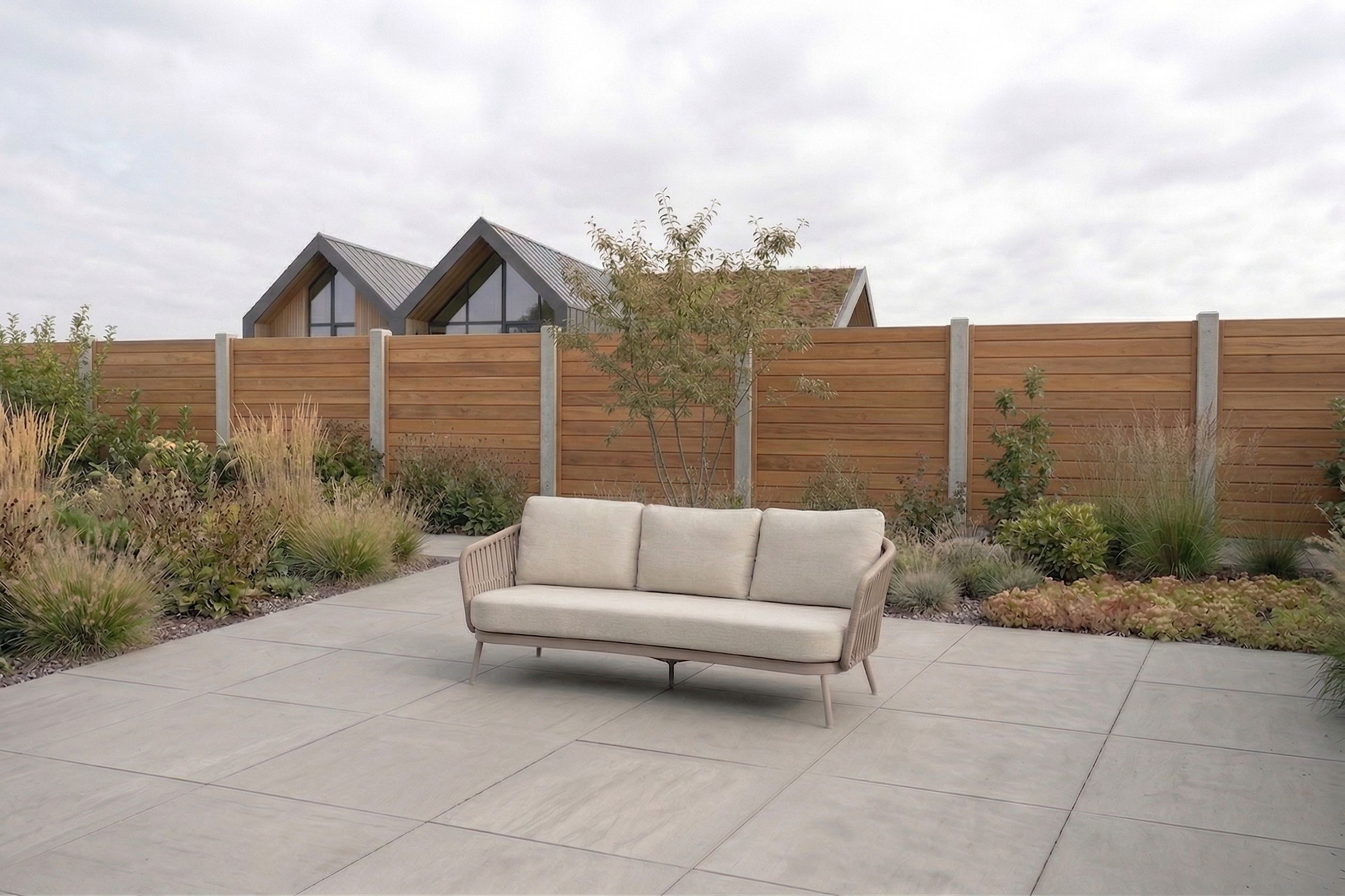Luxe 3-zits loungeset tuinbank van rope met beige kussens op een modern betegeld terras met houten schutting en beplanting.