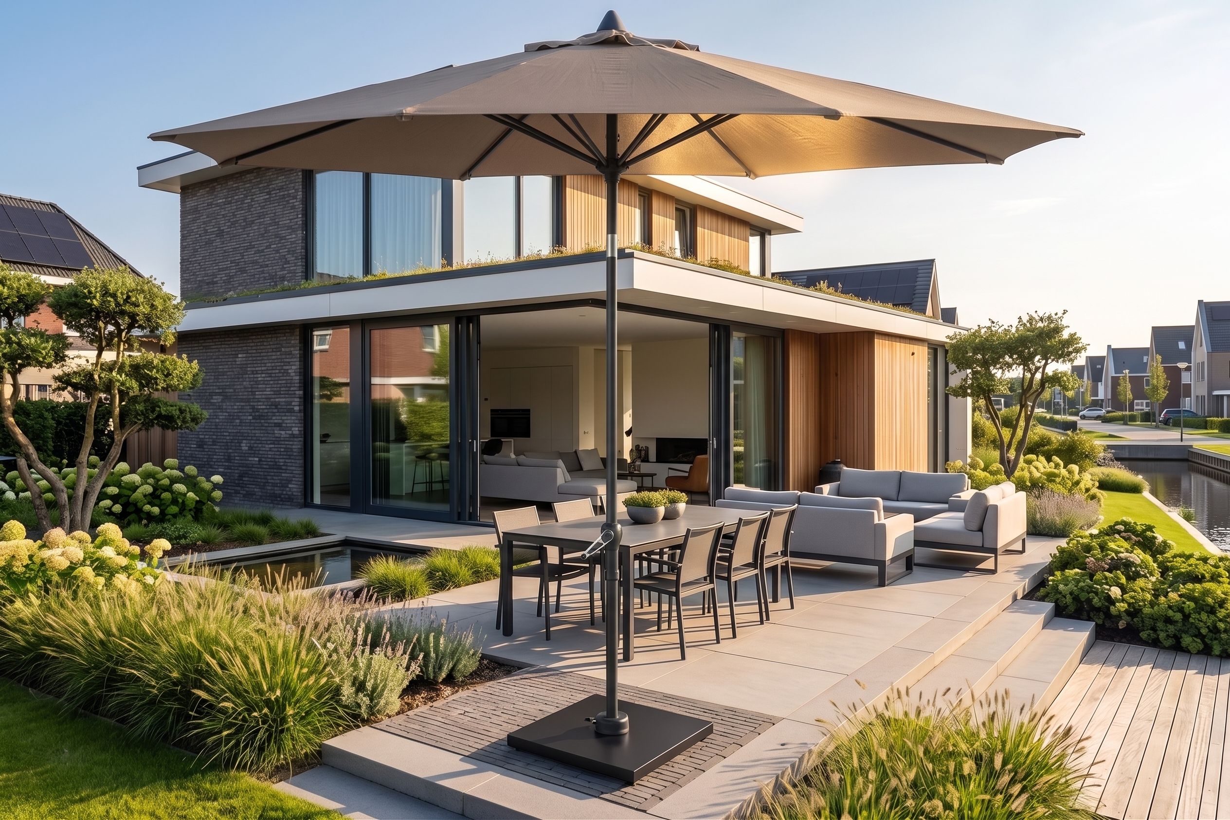Taupe stokparasol centraal geplaatst bij een luxe loungeset in een moderne achtertuin met vlonder.