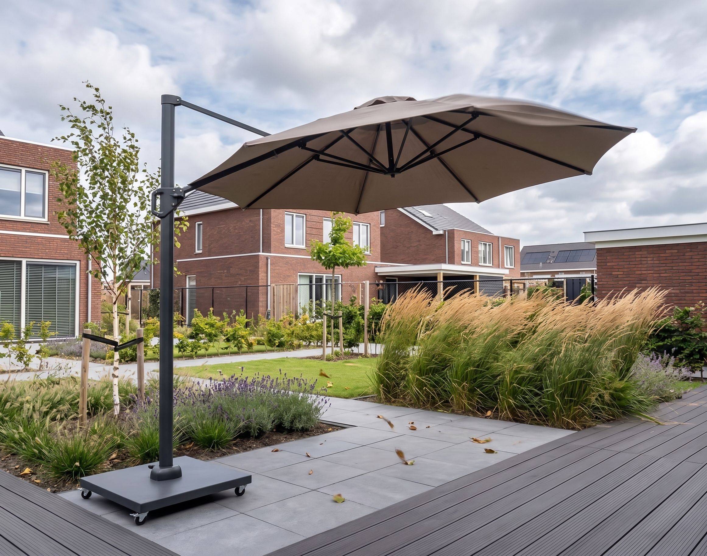 Windbestendige ronde zweefparasol op een verzwaarde verrijdbare voet die stabiel blijft staan tijdens windvlagen in een open tuin.