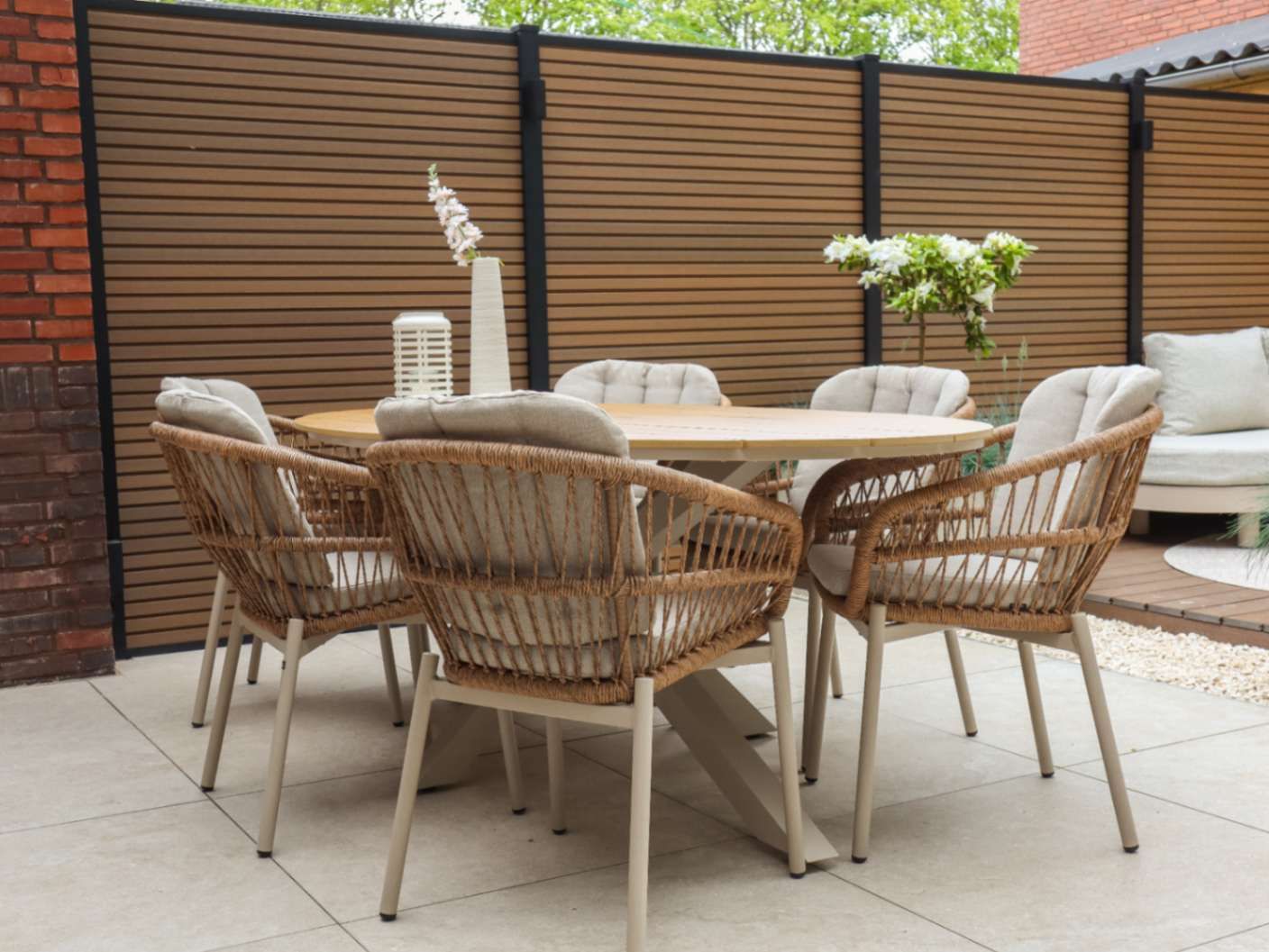 Ovale houten tuintafel met beige rope tuinstoelen in de achtertuin