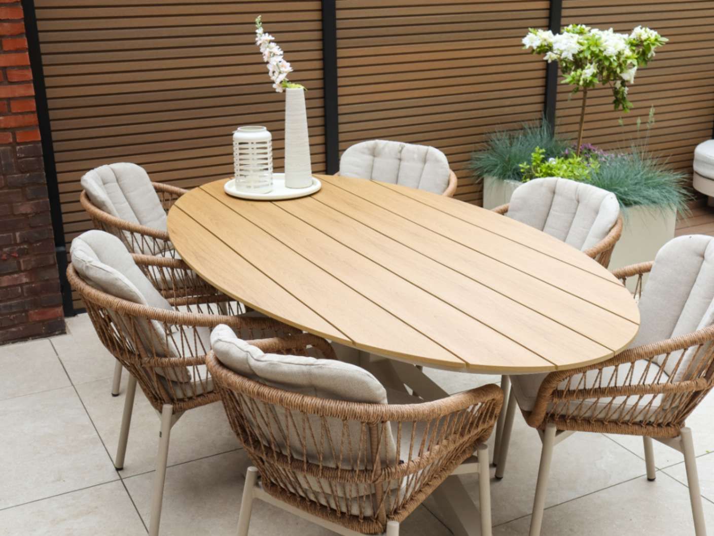 Houten ovale tuintafel met beige diningstoelen