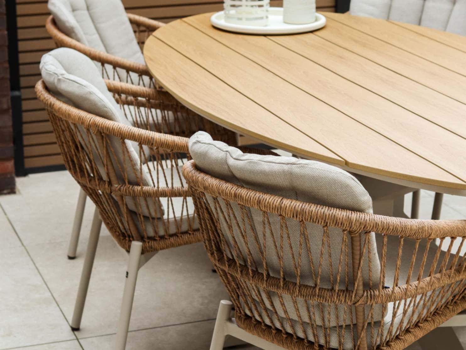 Detail van de ovale tuintafel en beige diningstoelen