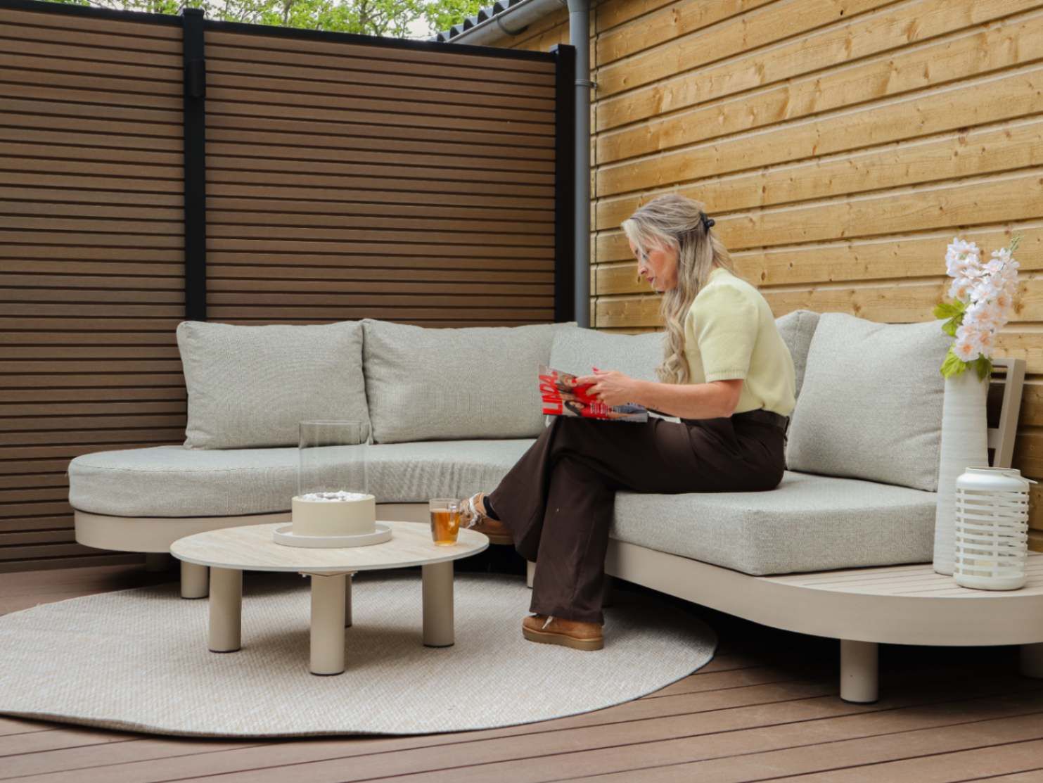 Nicole geniet van een moment op de beige loungeset in haar achtertuin