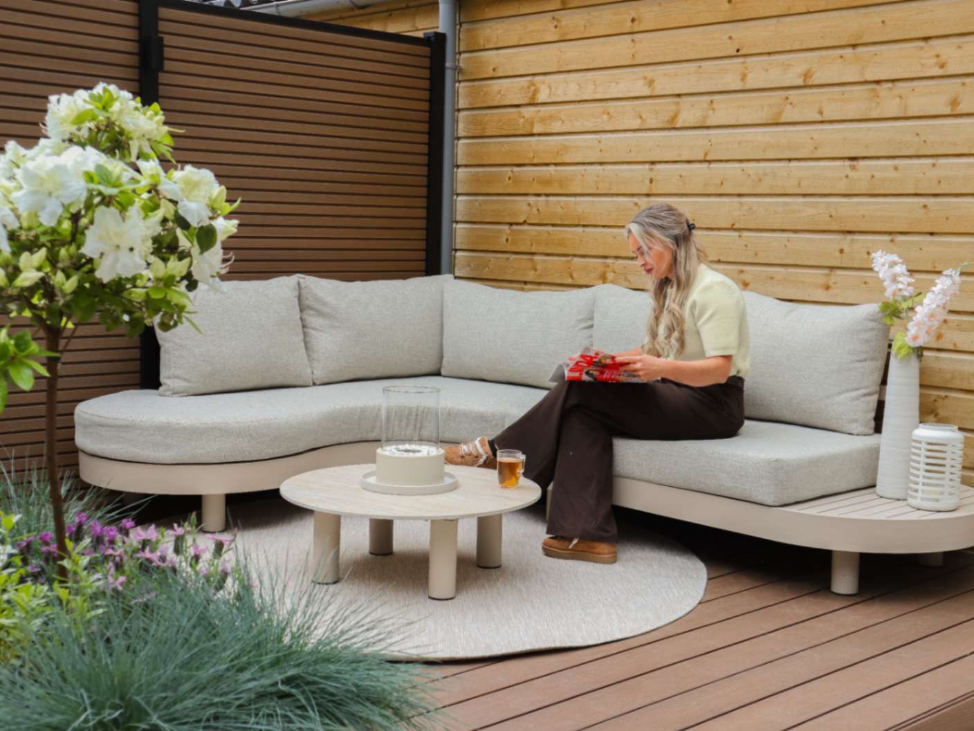 Nicole leest een magazine op de loungeset in de tuin