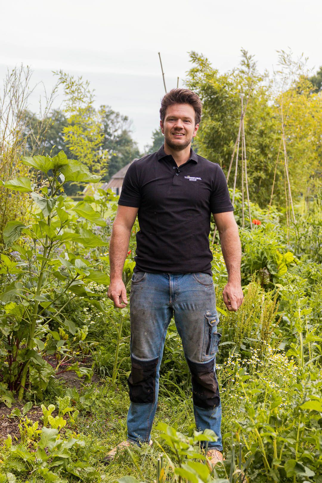 Man staat tussen groenten en kruiden in een moestuin