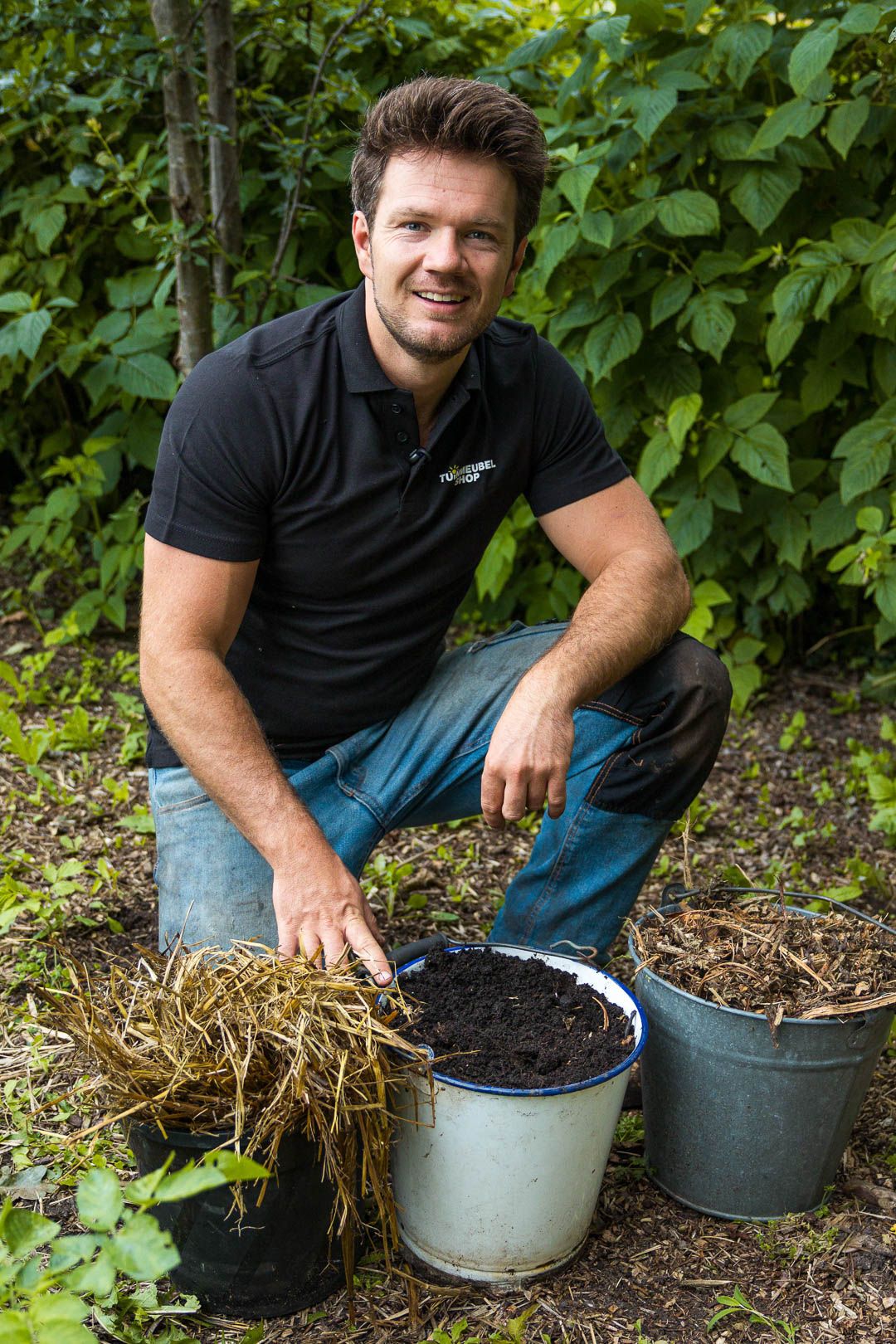 Man in moestuin met emmers compost en mulch