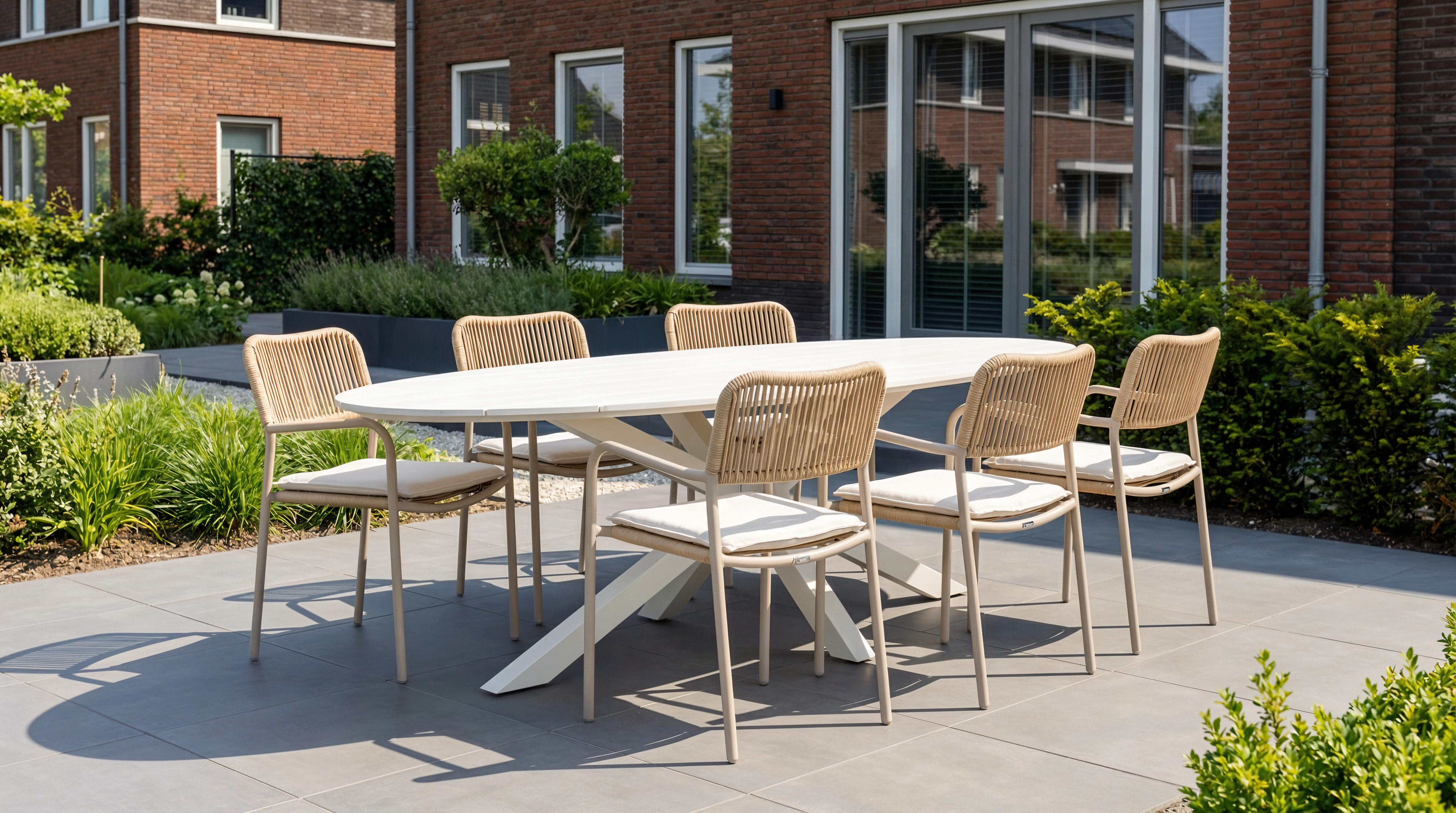 Coco Penya/Matara 220 cm dining tuinset (7-delig) met ovale tafel en 6 rope tuinstoelen in zandkleur, met zitkussens in een nieuwbouw tuin.