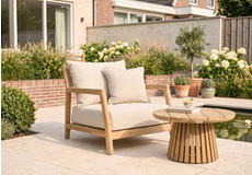 Moderne lounge tuinstoel met touw vlechtwerk en beige kussens op een houten terras met buitenkleed
