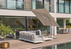 Moderne loungeset met grijze kussens en grote zweefparasol op een luxe terras bij het zwembad
