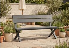 Houten tuinbank met rode zitkussen tegen een bakstenen muur, klassieke houten bank voor terras of tuin