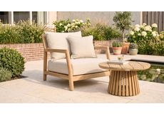 Moderne lounge tuinstoel met touw vlechtwerk en beige kussens op een houten terras met buitenkleed