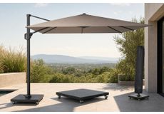 Zweefparasol met grijs doek naast een houten loungeset met kussens in een groene tuin