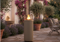 Design tuinhaard op hoge zuil met glasombouw, sfeervolle buitenhaard op een terras met mediterrane tuin