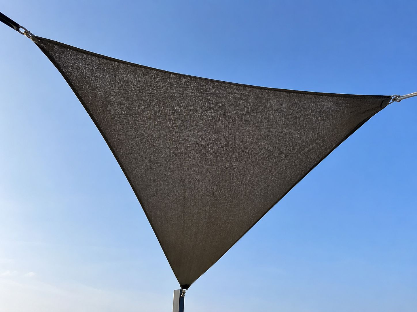 Antraciet vierkante zweefparasol met zijmast geplaatst bij een houten eethoek op een strak terras.