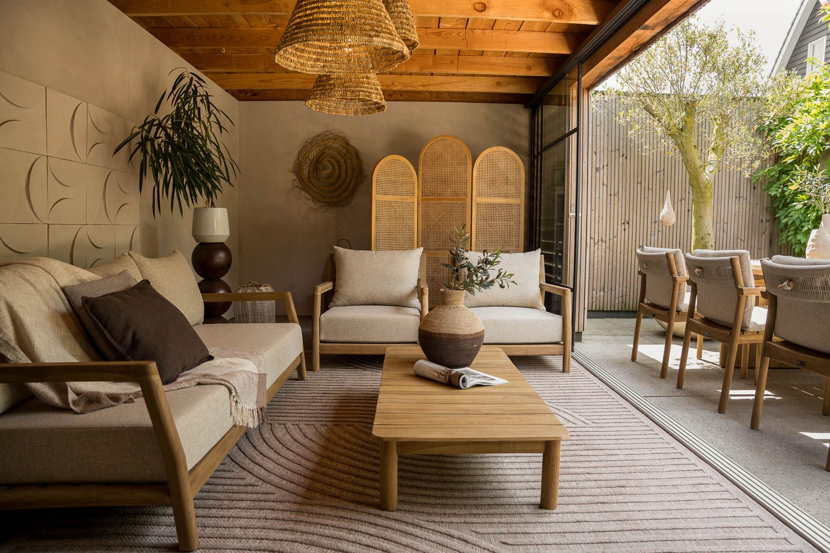 Japandi tuin met houten loungeset, lichte kussens en rustige beplanting