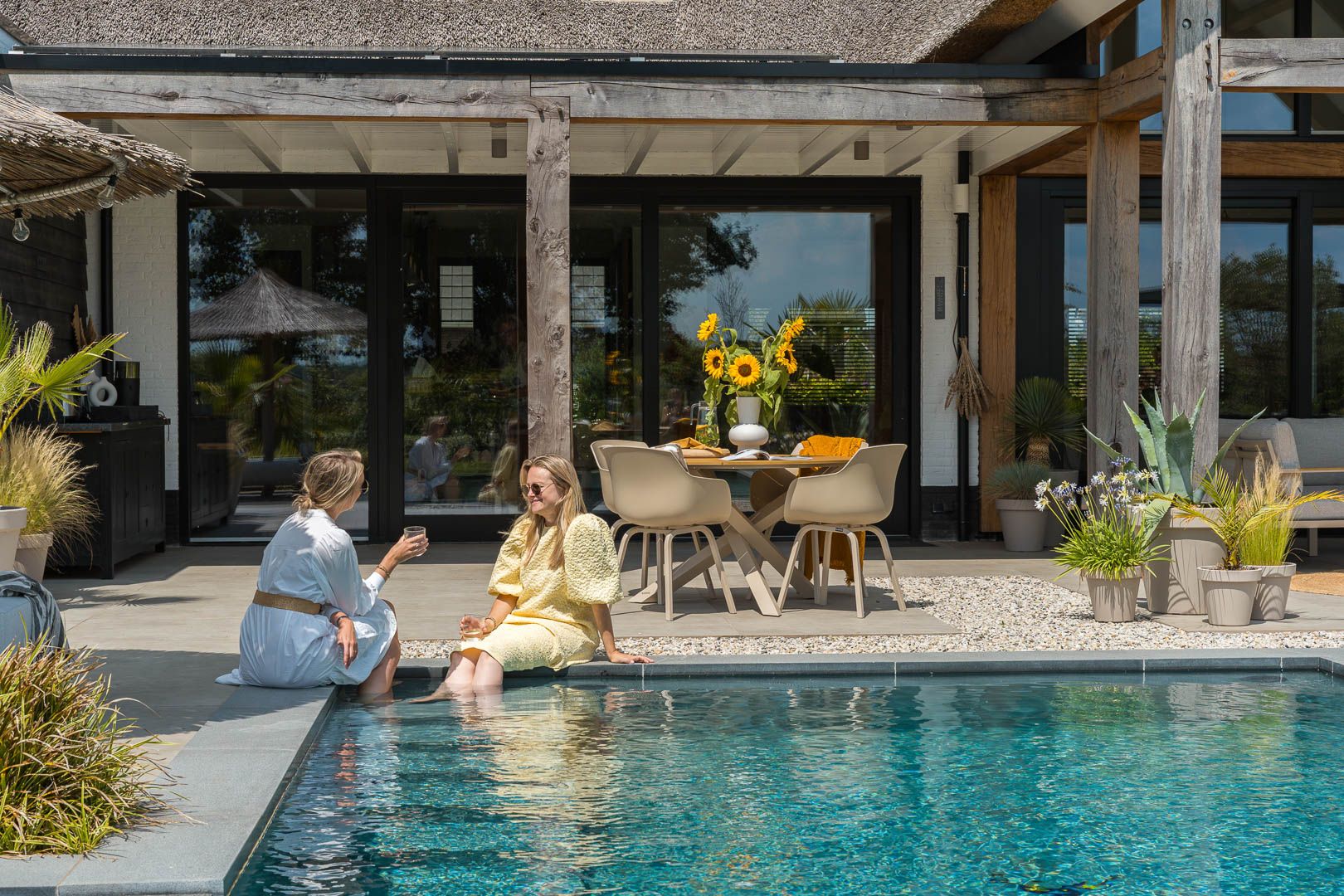 Twee vrouwen praten met hun voeten in het water in een moderne tuin